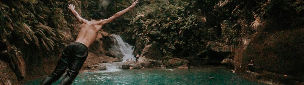 Man diving into a turquoise waterfall pool in Brazil, representing freedom and transformative experiences in nature.