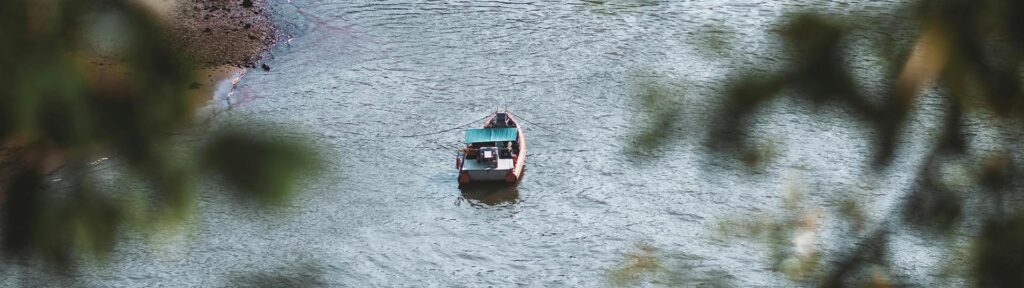 Boat floating on a calm Brazilian river framed by trees, evoking serenity, discovery, and introspection.