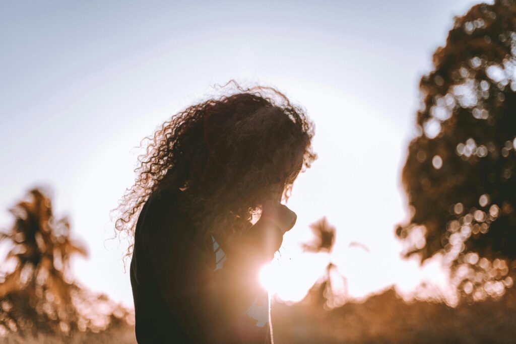 Silhouette of a woman with curly hair at sunset, symbolizing self-reflection and inner journey in Brazil.
